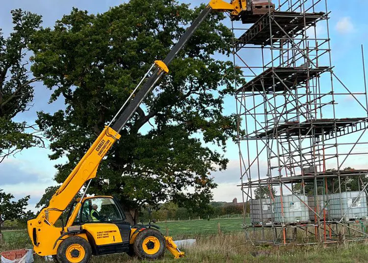 A yellow crane is lifting up a tree.