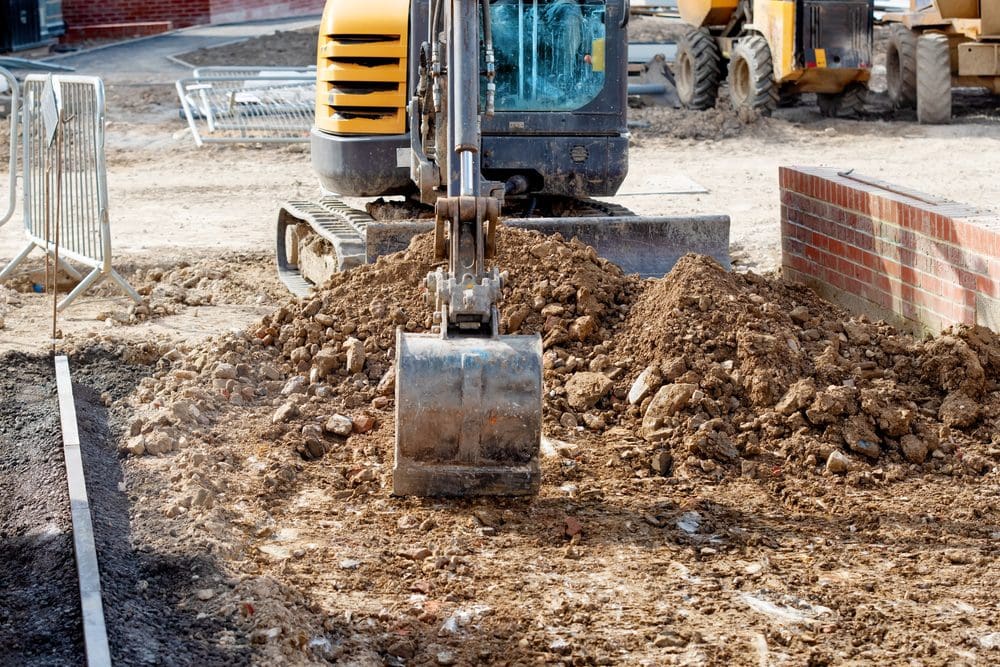 A small yellow and black tractor is digging dirt