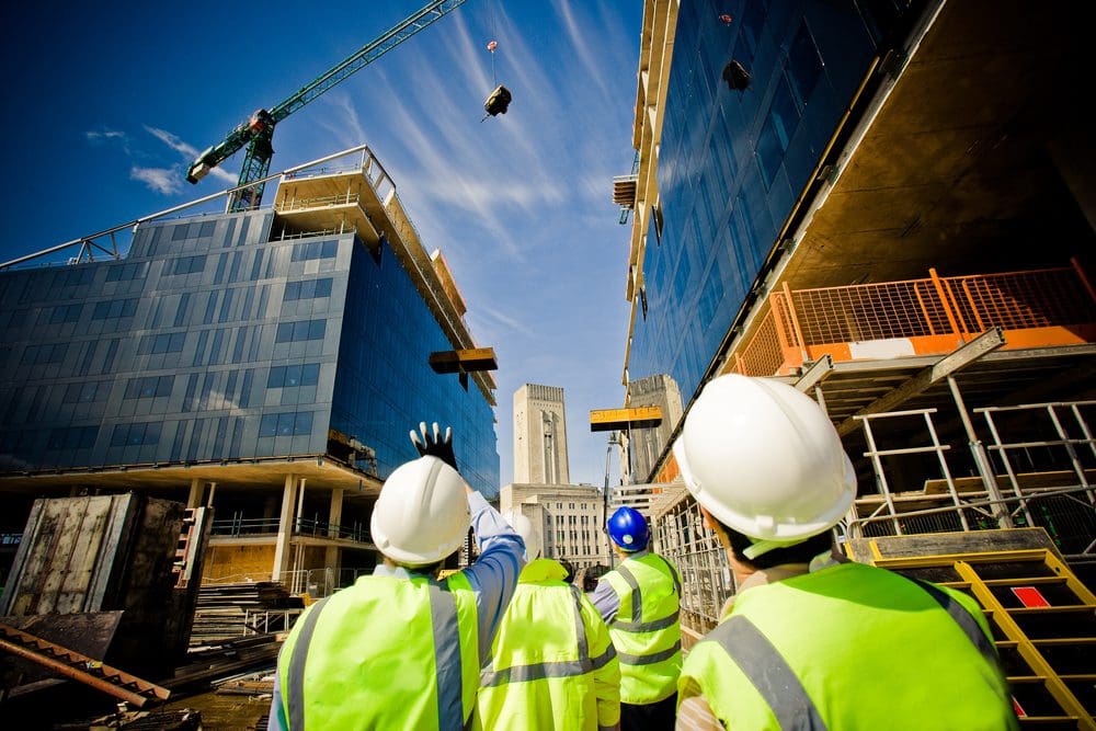 A group of construction workers standing on top of a building.